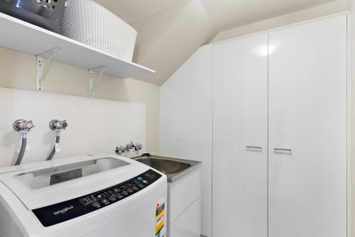 a white kitchen with a sink and a stove at Modern & Stylish 2 Bedroom Townhouse in Noosaville
