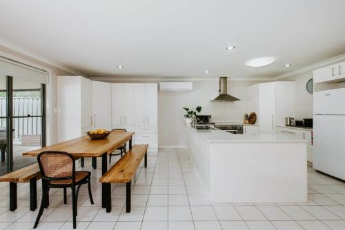 a white kitchen with a wooden table and chairs at Gladstone Blush - Premium Comfort in Mudgee's Heart in Mudgee
