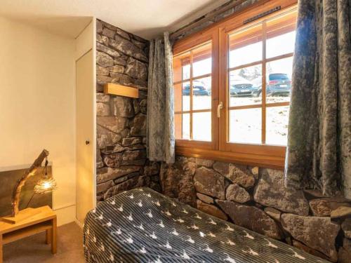 Zimmer mit einer Steinmauer, einem Sofa und einem Fenster in der Unterkunft Charmant 2 pièces à Valmorel avec balcon, linge de lit et ménage inclus, 4 pers. - FR-1-291-879 in Valmorel