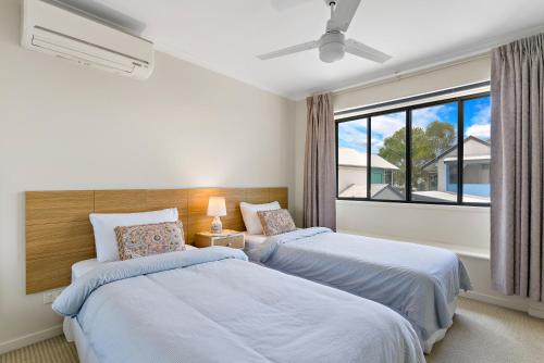 two beds in a bedroom with a window at Modern & Stylish 2 Bedroom Townhouse in Noosaville