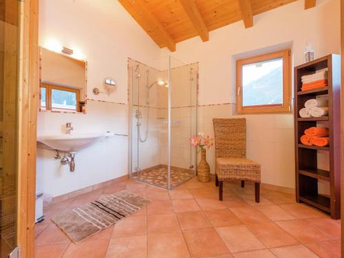 a bathroom with a shower and a sink and a chair at Chalet Wasserfall, Krimml in Krimml