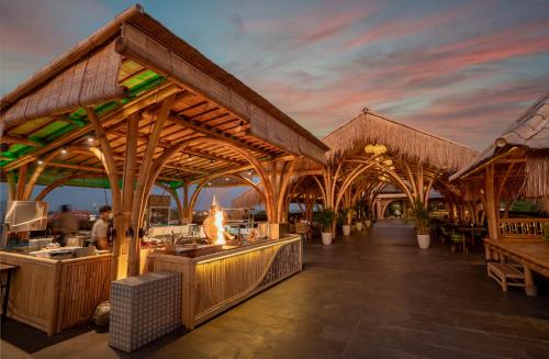 a restaurant with a large wooden pavilion with tables at The Nest Hotel Nusa Dua in Nusa Dua