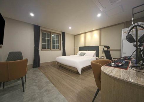 a hotel room with a bed and a table and chairs at H Avenue Hwamyeong in Busan