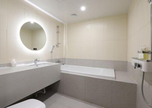 a bathroom with a tub and a toilet and a sink at H Avenue Hwamyeong in Busan