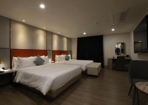 a large hotel room with two beds and a desk at H Avenue Hwamyeong in Busan