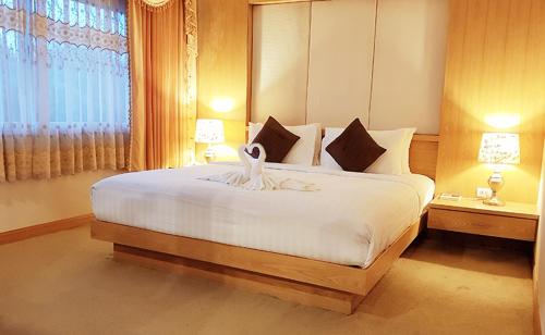 a bedroom with a large white bed with a window at Major Grand Hotel in Chum Phae