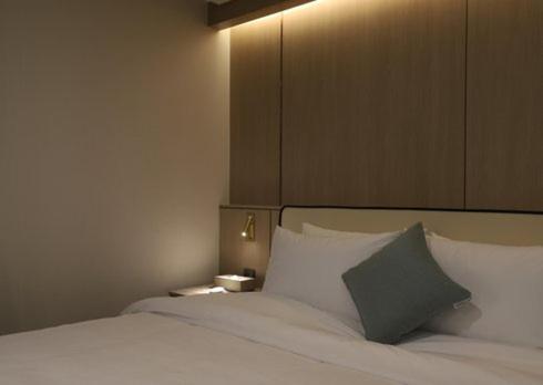 a bedroom with a white bed with a gray pillow at H Avenue Hwamyeong in Busan