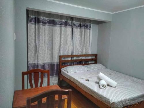 a bedroom with a bed and two chairs and a window at Cardo's Front Beach Room in General Luna