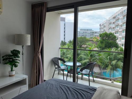 a bedroom with a bed and a window with a table and chairs at Laguna beach condo resort 3 maldives pattaya pool view ลากูน่า บีช คอนโด รีสอร์ต 3 พัทยา in Jomtien Beach