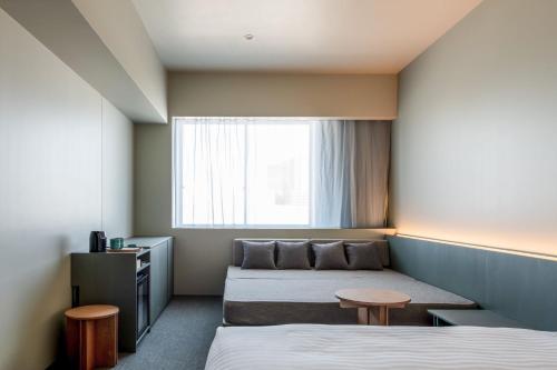 a hotel room with two beds and a window at KAIKA Tokyo by THE SHARE HOTELS in Tokyo