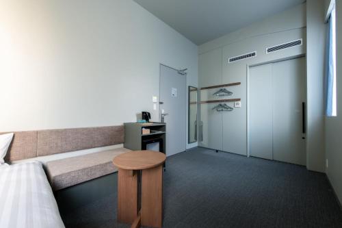 a room with a bed and a bench with a table at KAIKA Tokyo by THE SHARE HOTELS in Tokyo