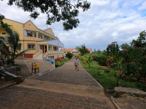 a man walking down a brick road in front of a building at Centre Lucien Botovasoa in Diego Suarez