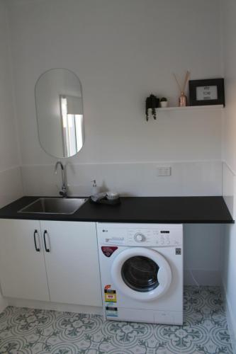 uma cozinha com um lavatório e uma máquina de lavar roupa em The Renmarkable Cottage em Renmark