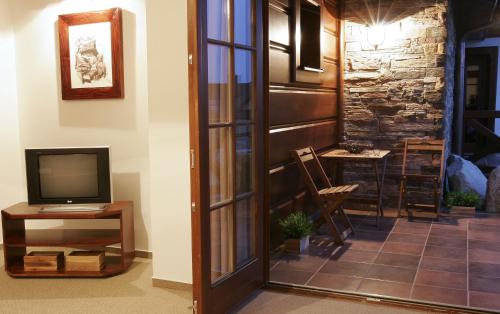 a living room with a tv and a door with a chair at Vila GRAND in Smokovce