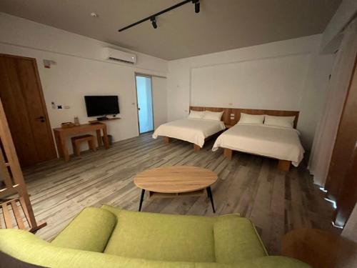 een kamer met 2 bedden, een bank en een tv bij Wutong Homestay in Huxi