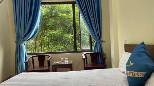 a bedroom with a bed and a window with blue curtains at Nhà Nghỉ Hương Trà Minh Đài 