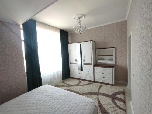 een slaapkamer met een bed, een dressoir en een raam bij Prestigious apartment in Bishkek in Bisjkek