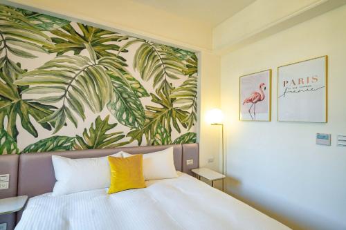 a bedroom with a bed with a tropical painting on the wall at Otis Inn in Hualien City
