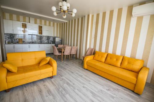 a living room with two yellow couches and a kitchen at Hotel "Sakvareli Sahli" Любимый дом in Tsikhisdziri