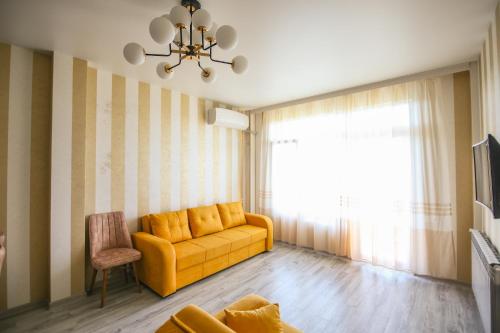 a living room with a yellow couch and a window at Hotel "Sakvareli Sahli" Любимый дом in Tsikhisdziri