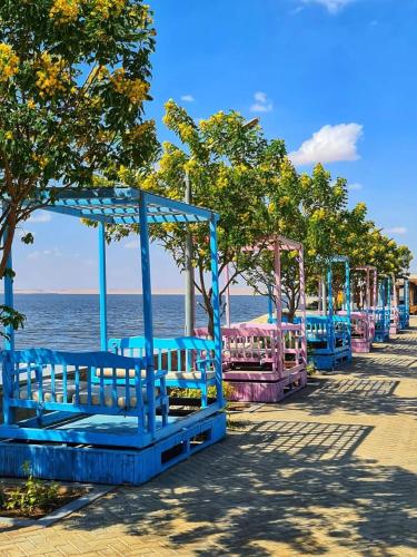 a row of blue benches next to the water at New Panorama Resort in Fayoum Center