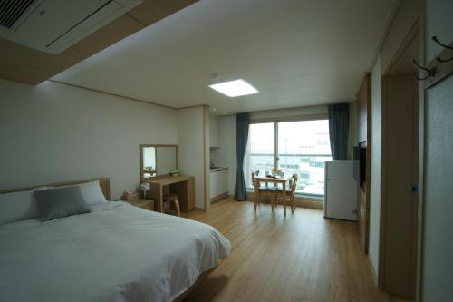 a bedroom with a bed and a table and a window at The Beach Pension in Jeju