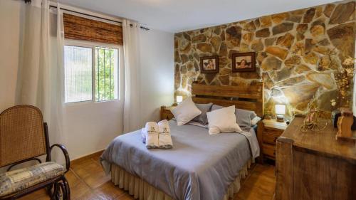 ein Schlafzimmer mit einem Bett und einer Steinmauer in der Unterkunft Casa Rural la Sacri Guaro by Ruralidays in Guaro