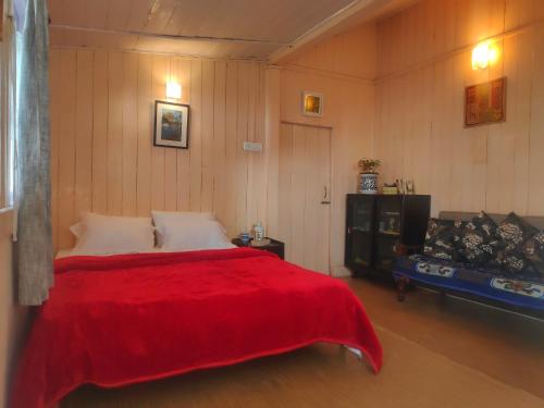 - une chambre avec un lit et une couverture rouge dans l'établissement Darjeeling BnB, à Darjeeling