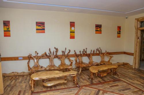 a room with four wooden chairs and a wall with paintings at Dovenest Lodge in Naivasha