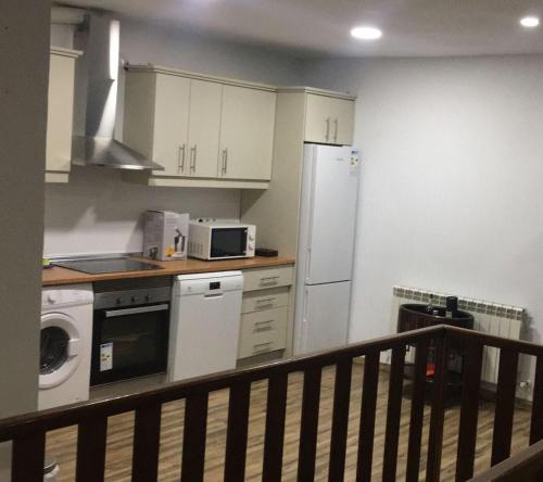 a kitchen with white cabinets and a white refrigerator at Apartamentos el soho in Avila