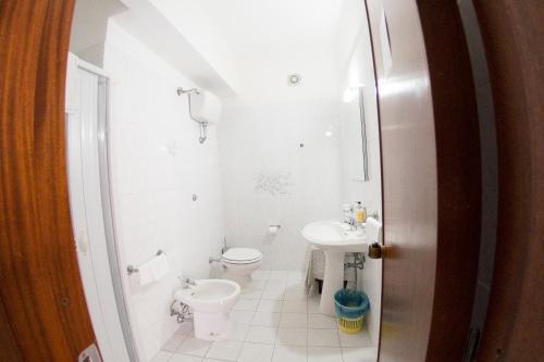 a white bathroom with a toilet and a sink at Hotel Eden in San Domino