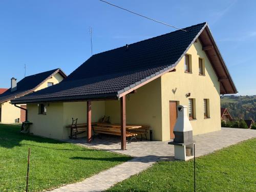 a house with a black roof with a picnic table at Domki pod Beskidem in Jaworzynka