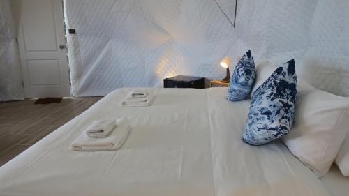 a white bed with blue and white pillows on it at Touch Glamping Koh Yao Noi ทัช แกรมปิ้ง เกาะยาวน้อย in Ko Yao Noi