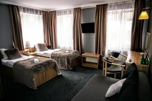 a hotel room with two beds and a chair at Aviator Hotel Restauracja & SPA in Pabianice