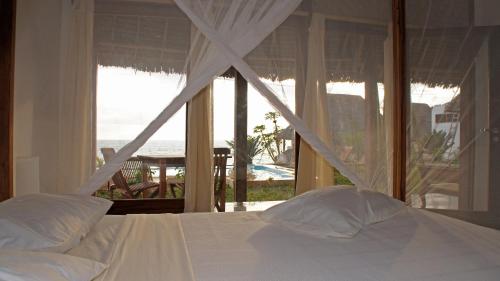 a bedroom with a bed with a view of the ocean at Art Hotel Zanzibar in Jambiani