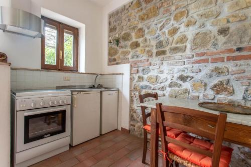 uma cozinha com uma mesa e uma parede de pedra em Angela - Agriturismo La Valentina em Talamone