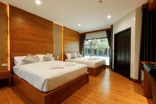 a bedroom with two beds and a large window at บีวินรีสอร์ท in Nakhon Si Thammarat