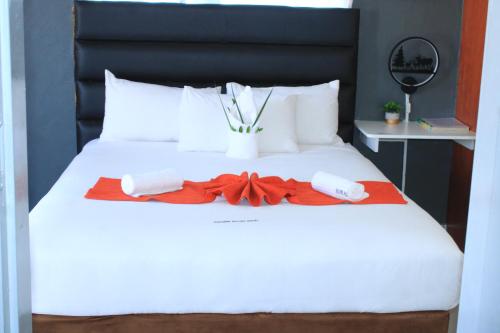 a white bed with two towels and a vase on it at Shalakwe Hills-Inn Guesthouse Kasane in Kasane