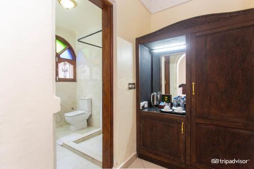 a bathroom with a toilet and a wooden door at Al-Minar Hotel in Zanzibar City