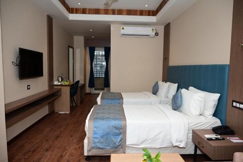a hotel room with two beds and a television at PIPUL PADMAJA PRIDE in Cuttack