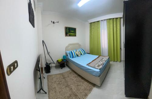 Your Home in Madinaty في Madīnat ash Shurūq: غرفة نوم صغيرة مع سرير وستارة خضراء