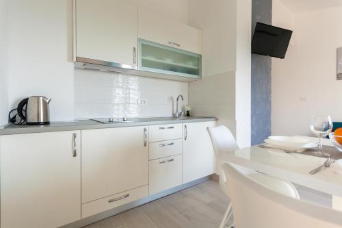 uma cozinha com armários brancos e uma mesa e cadeiras em Apartments Didi em Omišalj