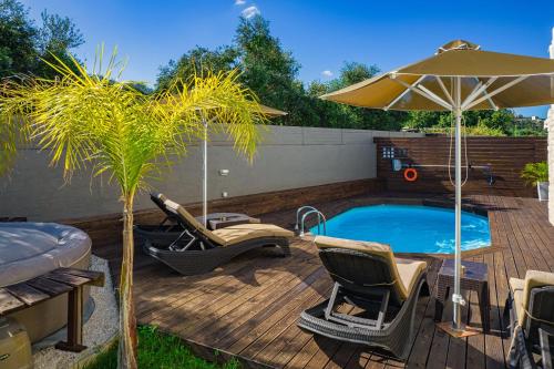 a deck with a pool and chairs and an umbrella at Cocoon Luxury Villas in Maleme