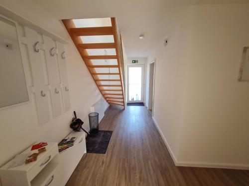 a hallway with a staircase in a room with wooden floors at Ferienwohnung am Rursee in Simmerath