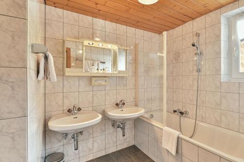a bathroom with two sinks and a shower and a tub at Apartmenthaus Steiner in Lech am Arlberg