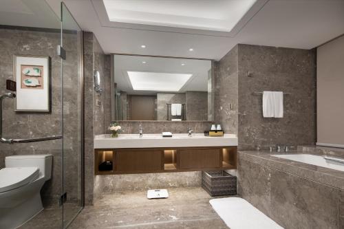 bagno con lavandino, servizi igienici e specchio di White Swan Hotel Taizhou a Taizhou