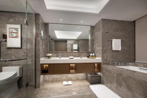 a bathroom with a sink and a toilet and a mirror at White Swan Hotel Taizhou in Taizhou