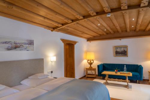 um quarto com uma cama e um sofá azul em Hotel Ziegleder em Rottach-Egern