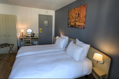 a bedroom with a large bed with white sheets and pillows at Grand Hôtel d'Espagne in Lourdes