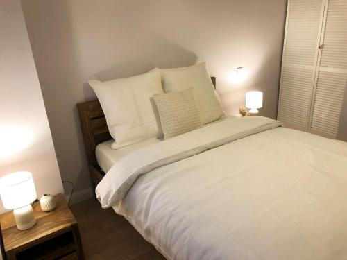 a bedroom with a bed with white sheets and pillows at Au coeur de l'Alsace - Gîtes in Bennwihr